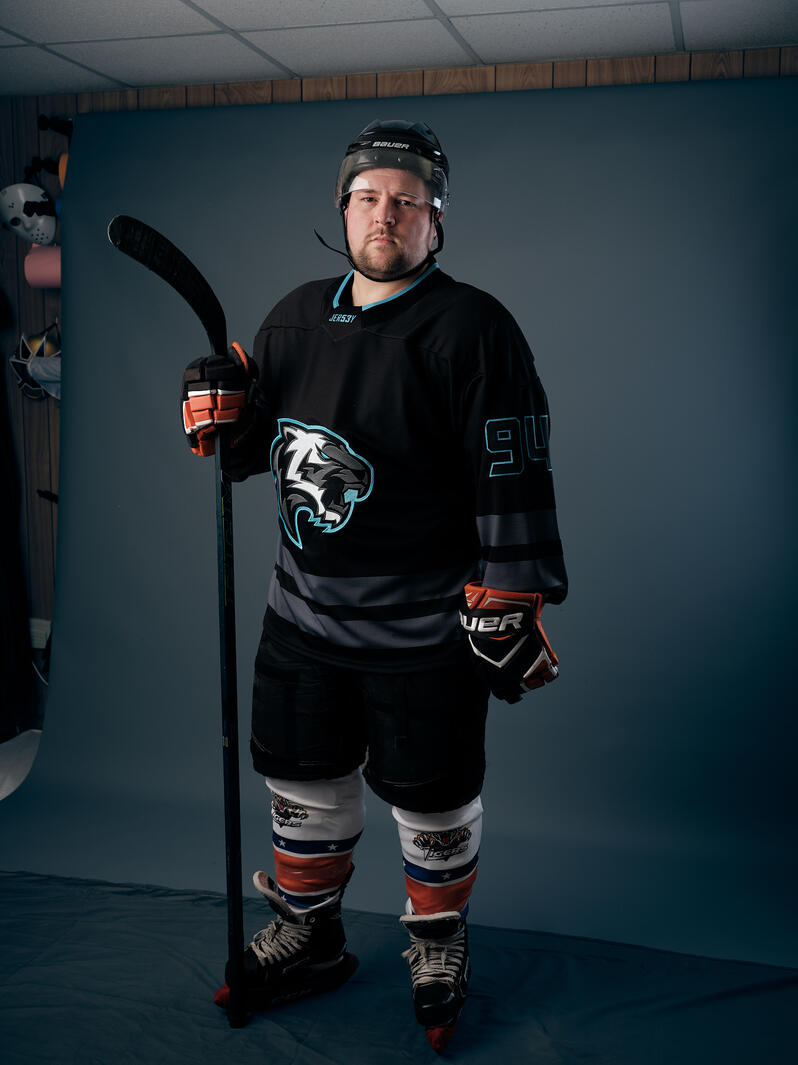 A mid-30's male dressed in ice hockey gear in a photo studio